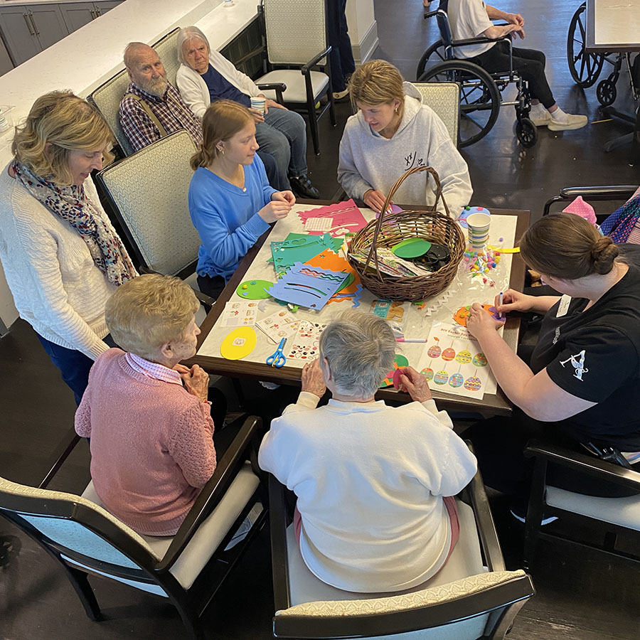 Volunteers assist memory care residents with Easter crafts.