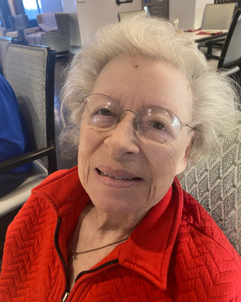 Smiling Joann, a senior lady with glasses and a red jacket.