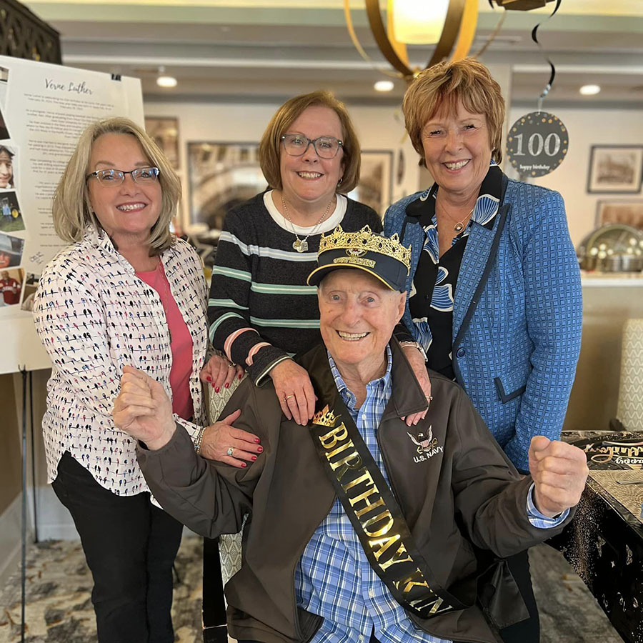 Three women and an older man smiling for a photo, celebrating Verne's "25th" birthday, as he turns 100 today!